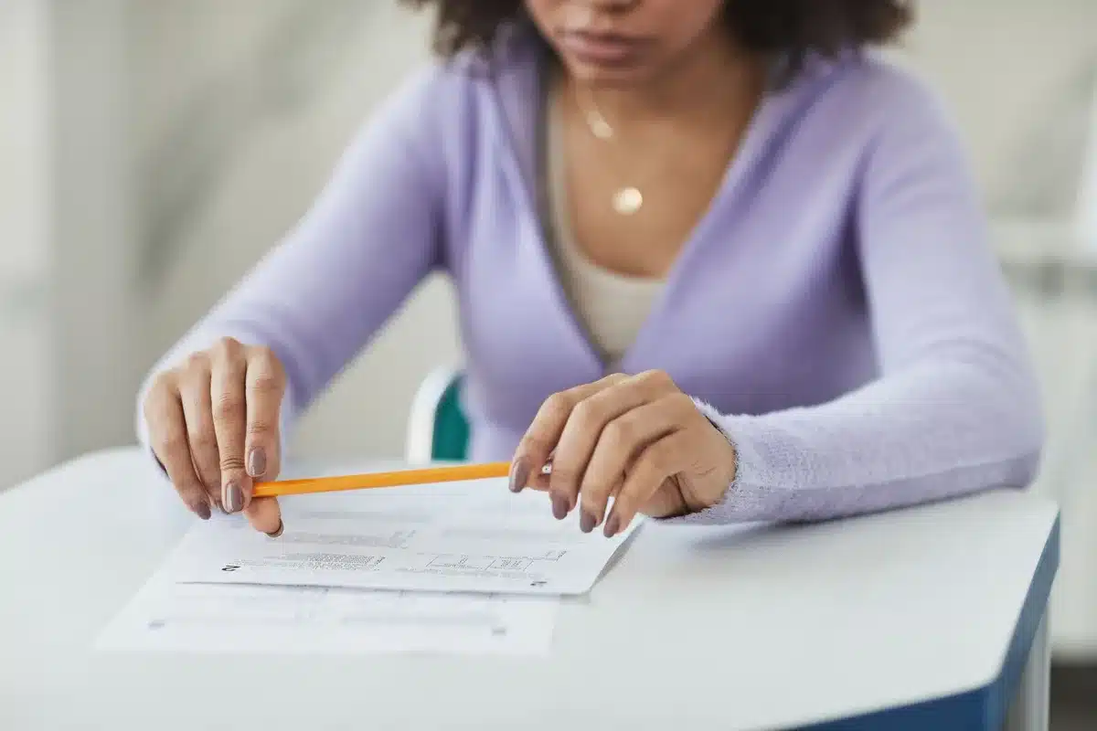 Candidatos anónimos realizando un examen en una sala institucional con papeles y lápices