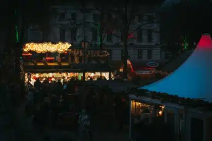 Multitud de personas disfrutando en una plaza festiva con cervezas, iluminación nocturna y ambiente de celebración veran