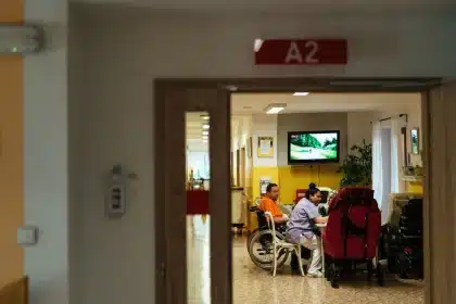 Sala de espera de hospital con paciente sentado, reloj de pared visible