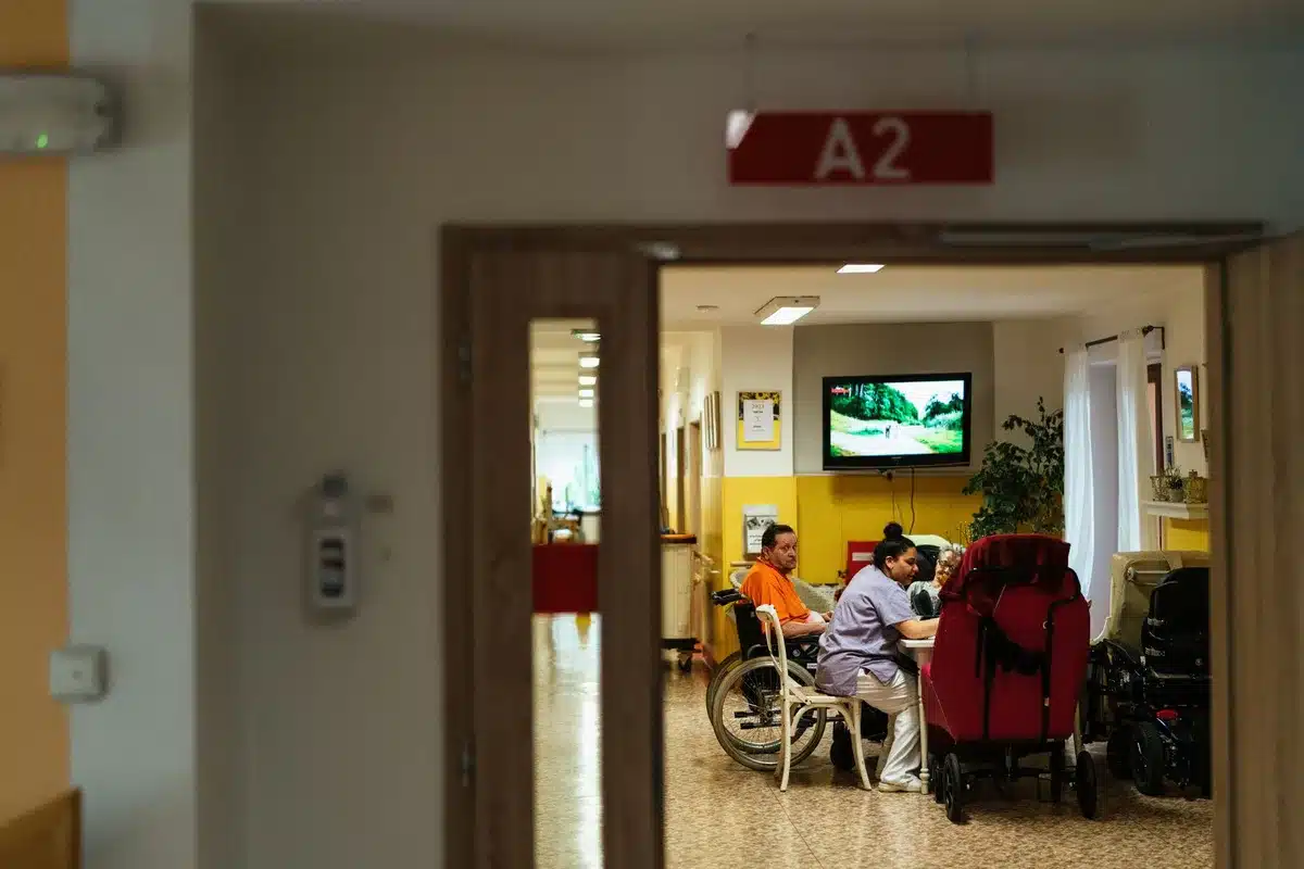 Sala de espera de hospital con paciente sentado, reloj de pared visible