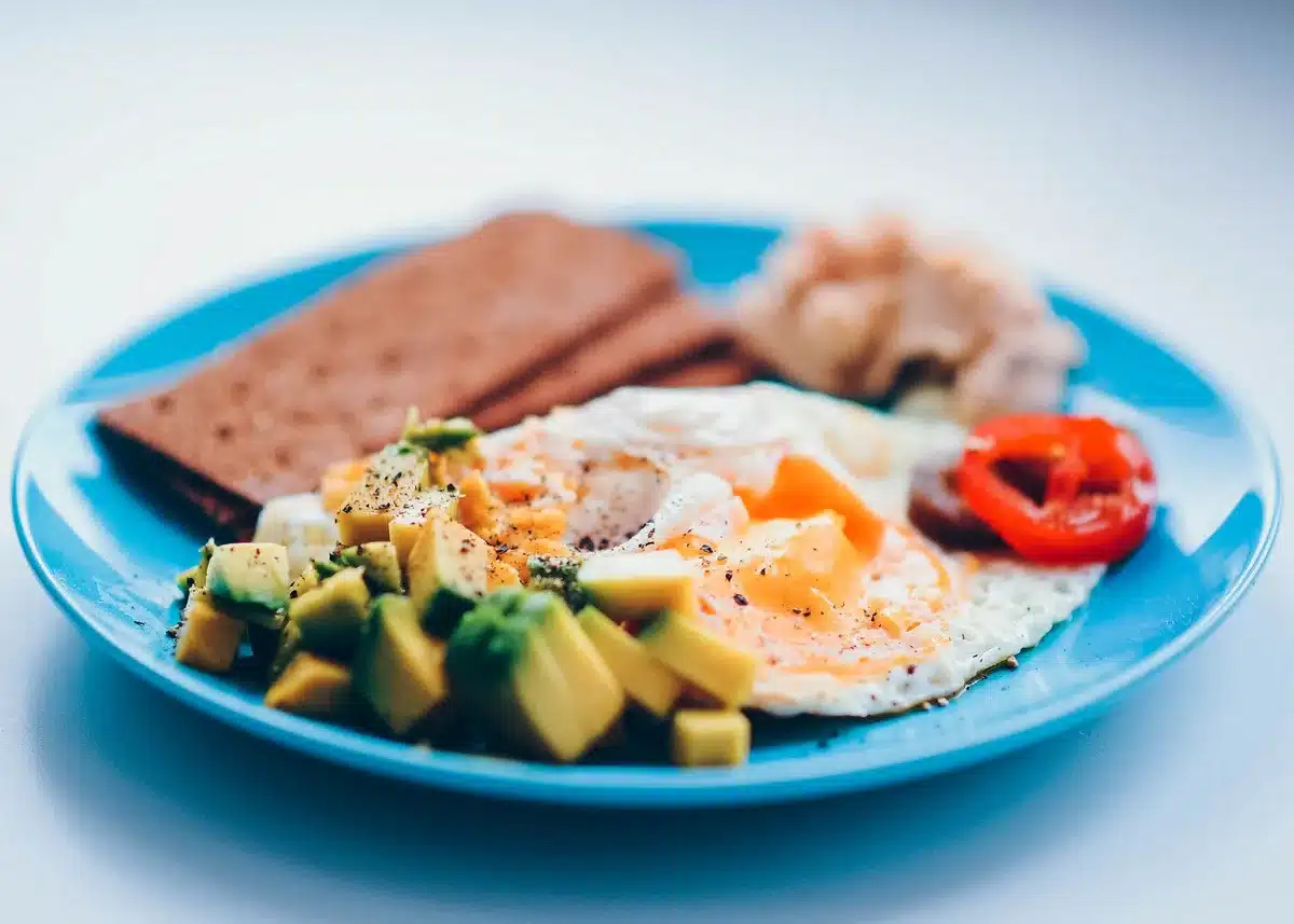Desayuno nutritivo con huevos, aguacate y pan integral en un plato