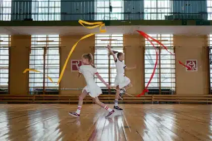 Gimnastas de rítmica en formación ejecutando una rutina con cinco pelotas en el aire.