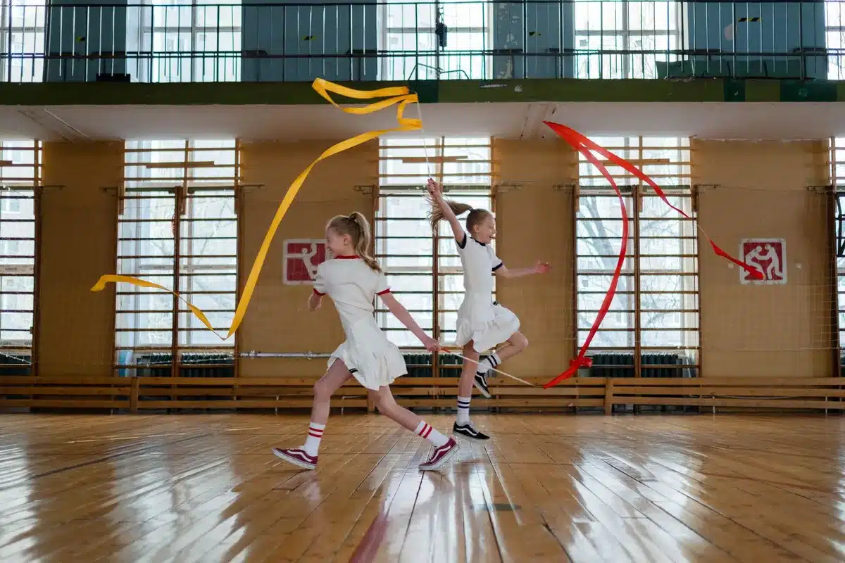 Gimnastas de rítmica en formación ejecutando una rutina con cinco pelotas en el aire.
