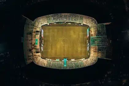 Multitud en un estadio de fútbol durante un partido nocturno, con luces de floodlights
