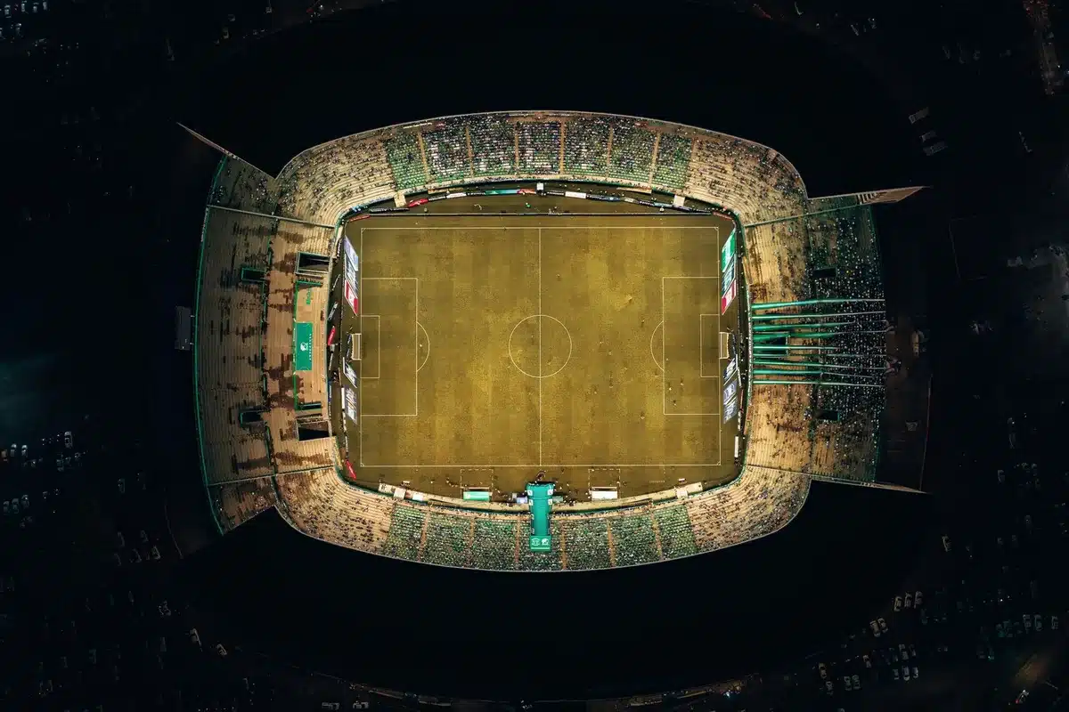 Multitud en un estadio de fútbol durante un partido nocturno, con luces de floodlights