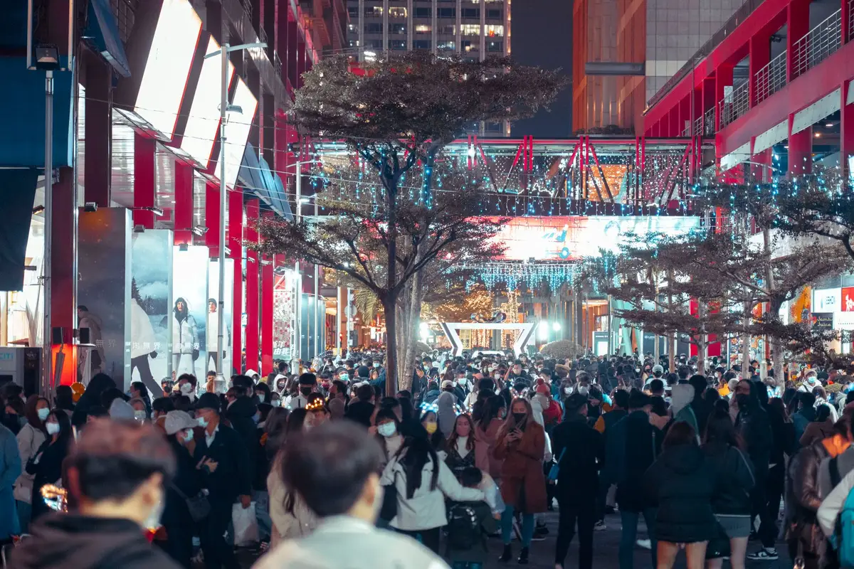 Multitud celebrando en una plaza con banderas y confeti al atardecer