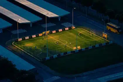 Joven futbolista en instalaciones de cantera moderna con equipo técnico