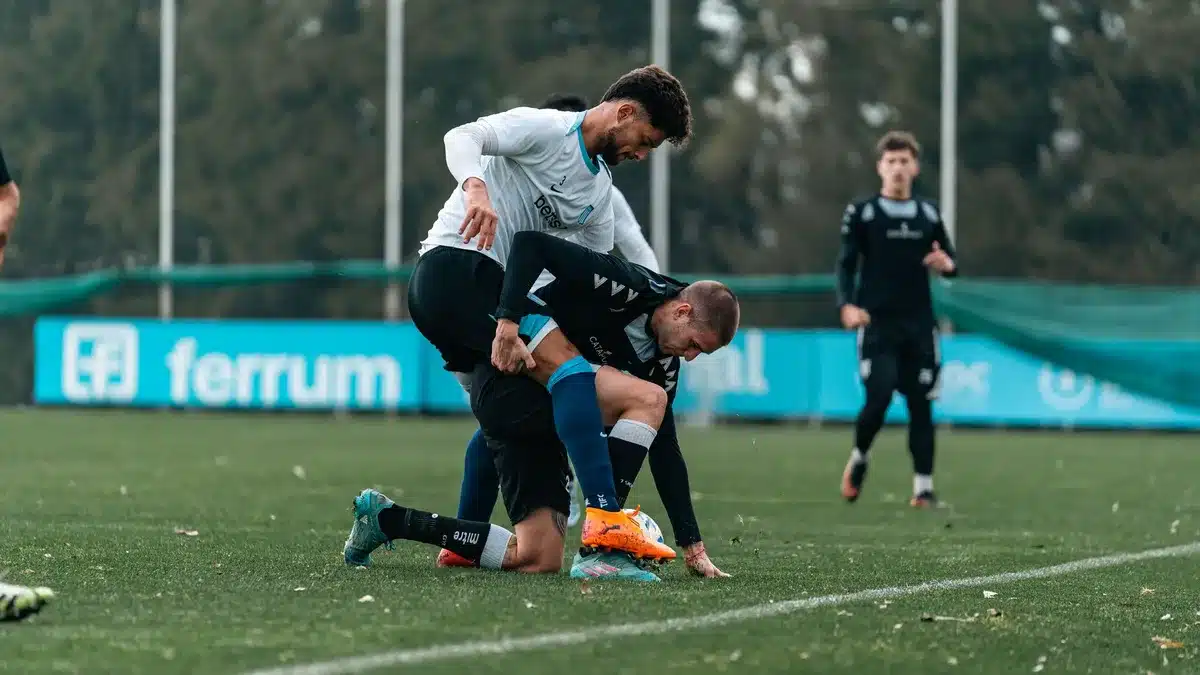 Jugadores de dos equipos en contacto físico intenso durante un partido de fútbol tenso.