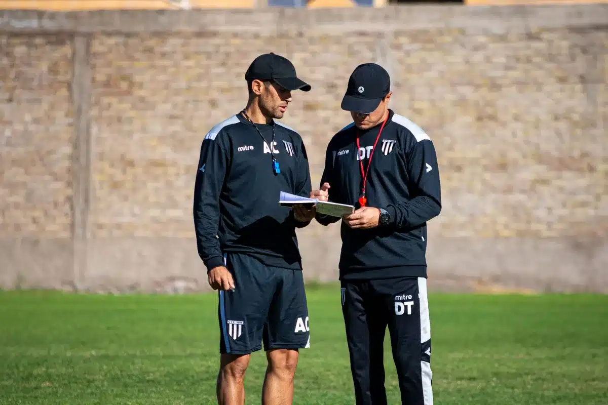 Entrenador de f&uacute;tbol analizando t&aacute;ctica de posesi&oacute;n en pizarra