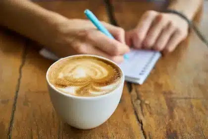Cuaderno con poemas junto a una taza de té y una ventana con lluvia