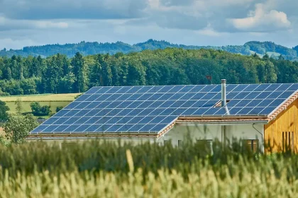Grupo anónimo trabajando en huerto comunitario junto a paneles solares y casas de piedra