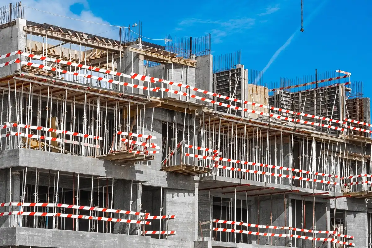 Trabajadores de construcción en un yacimiento de obra con andamios y paredes en proceso de construcción.