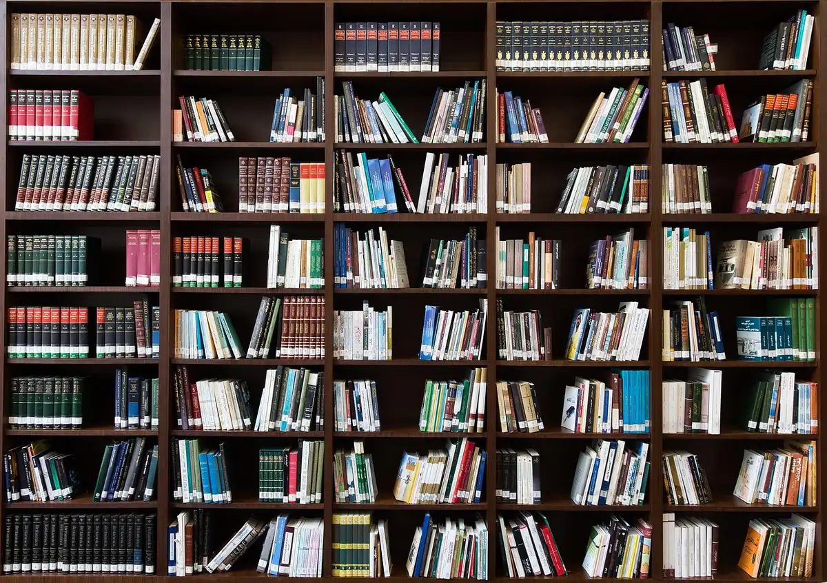 Estanterías con libros y manos que sacan un volumen