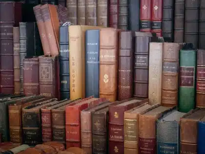 Estudiante concentrado leyendo un libro en la biblioteca, con el móvil de fondo