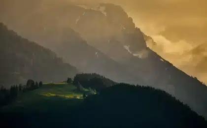 Vehículos y buldócer trabajando al amanecer junto a un monte con humo leve