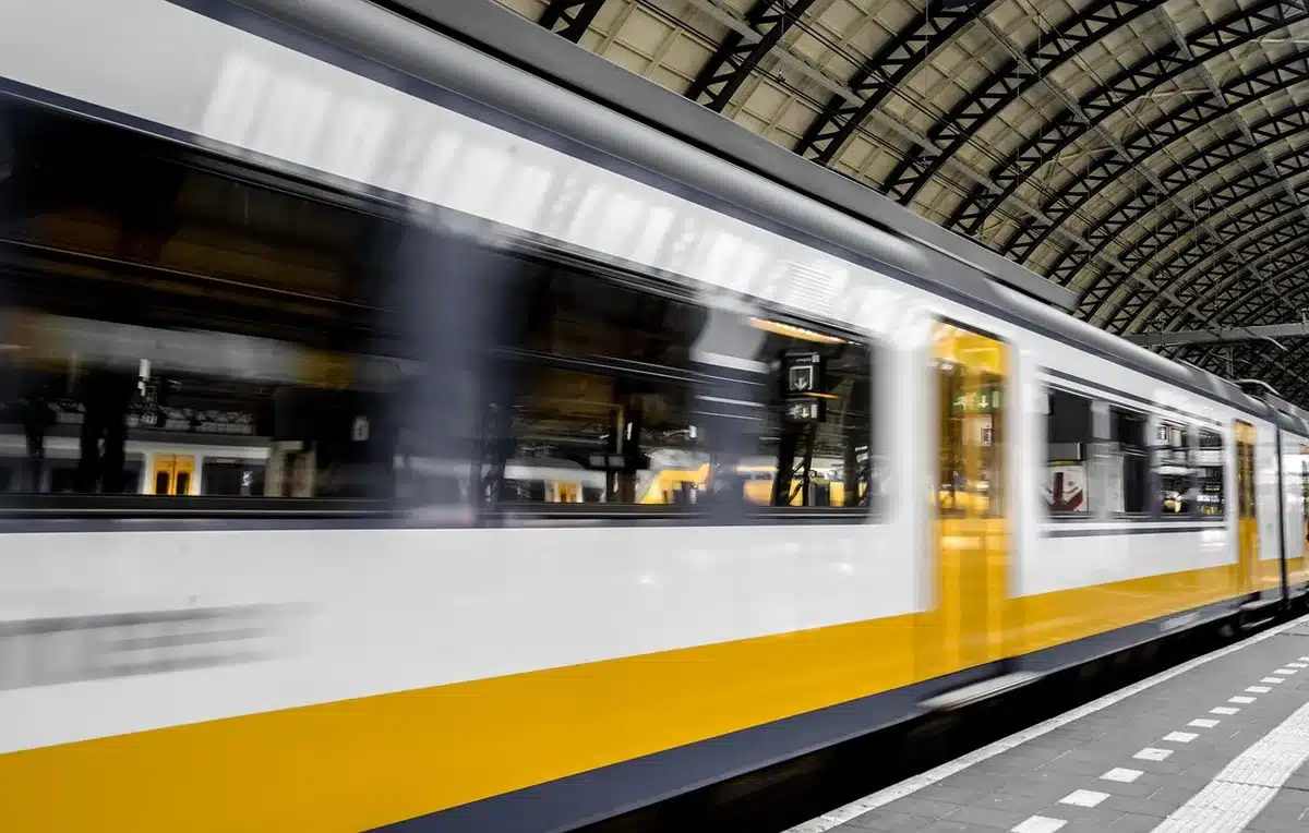 Viajeros esperando en andén de estación con retrasos por limitaciones de velocidad