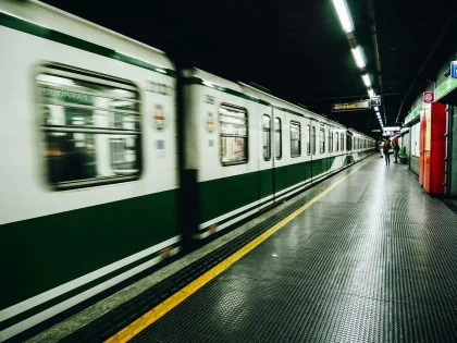 Plataforma de estación con trenes en marcha lenta por limitaciones de velocidad durante trabajos de reparación estructur