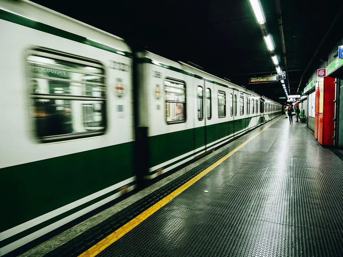 Plataforma de estación con trenes en marcha lenta por limitaciones de velocidad durante trabajos de reparación estructur