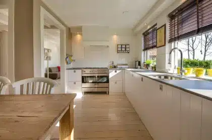 Mesa de cocina con reloj y electrodomésticos, luz solar entrando por la ventana