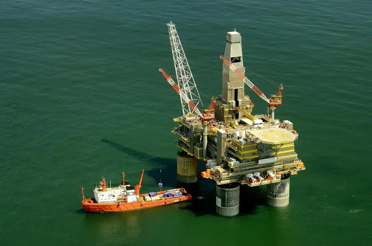 Plataformas petroleras genéricas en la costa con técnicos anónimos observando equipos