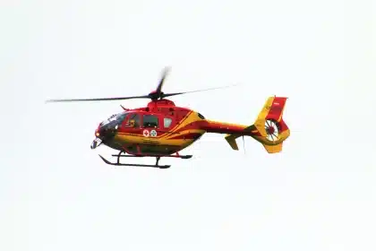 Orilla inundada con escombros, personal de rescate y un helicóptero en el cielo