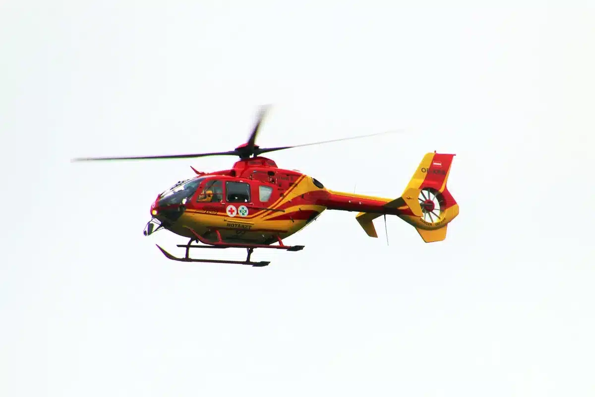 Orilla inundada con escombros, personal de rescate y un helicóptero en el cielo